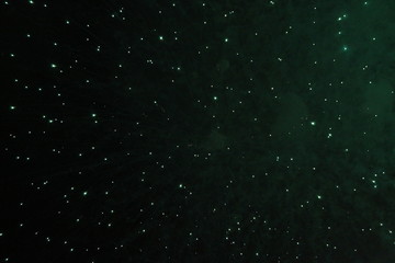 Obraz premium A scattering of stars and bright green shiny lights of fireworks during Halloween, Christmas, Independence Day, New Year.
