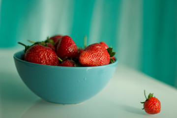 Fresh strawberries in a porcelain bowl on the table.