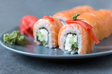 Philadelphia rolls with salmon, ginger and wasabi on a grey plate on a dark background