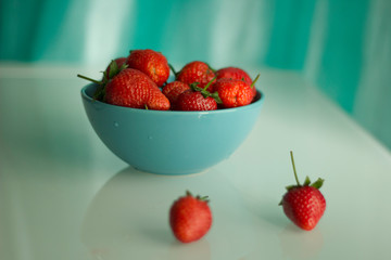 Fresh strawberries in a porcelain bowl on the table.