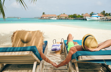 Couple at beach on wooden sun bed loungers
