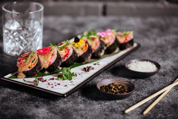 Various kinds of tasty sushi served on black stone