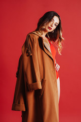 Fashion portrait of young woman in jacket and red swimsuit. Pink background, studio shot