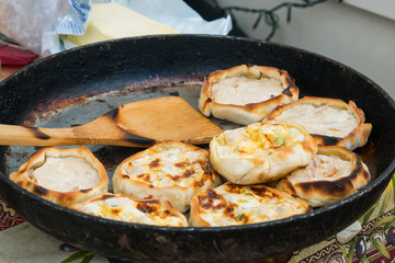 Process of cooking hot mini pies with chicken and cheese at street food festival. Outdoor cooking, service, gastronomy and takeaway food concept