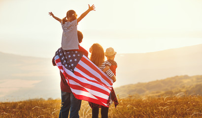 happy family with flag of america USA at sunset outdoors.