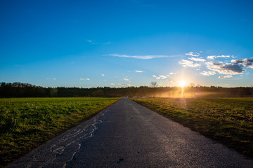 Asphalt road in countryside on sunset