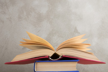 Education and reading concept - group of colorful books on the wooden table, concrete wall blackboard