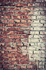 Grungy toned brick wall half in white paint