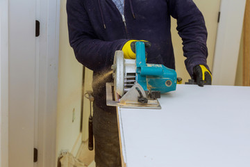 Man hands holding circular saw and preparing to make a cut in door