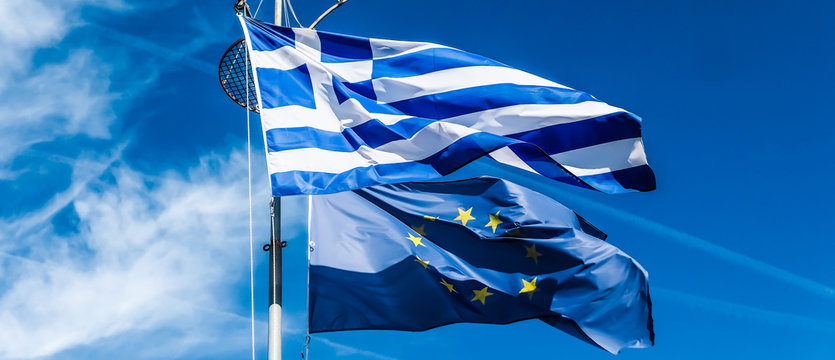 Flags of Greece and European Union on blue sky background, politics of Europe