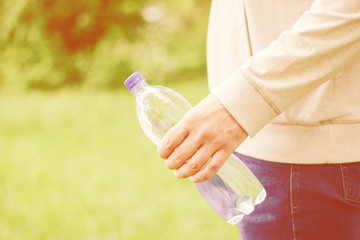 man hipster holding a plastic bottle with water in nature. healthy lifestyle, summer, heat.  Walk in the park.