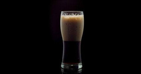 Dark craft beer brewed from malt and barley in a private brewery on a black background