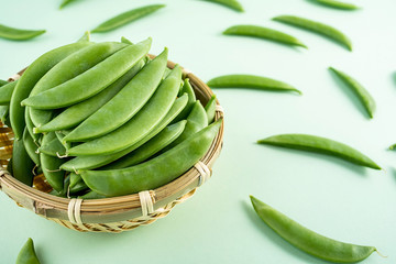 Fresh bean pod vegetable sweet beans on a bamboo sieve on a light green background
