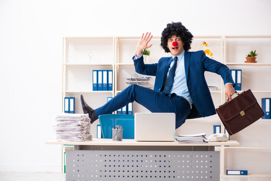 Young clown businessman working in the office 