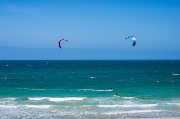 Open ocean landscape with kite surfers with colorful parachutes