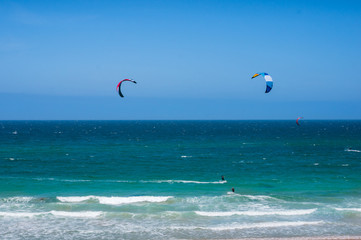 Open ocean landscape with kite surfers with colorful parachutes
