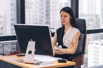 working woman sitting looking computer monitor and work with document on desk in office building