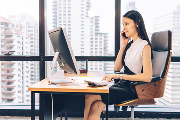 Business Woman talking with mobile phone on her desk in Modern office building