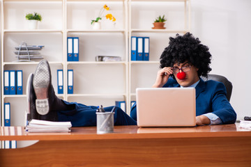 Young clown businessman working in the office 