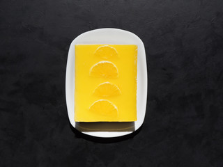 Yellow cheesecake with oranges on black background