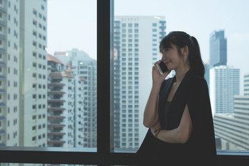 Business Woman talking with mobile phone near glass windows  in Modern office building