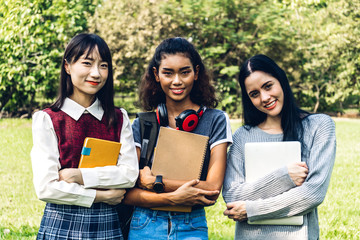 Group of smiling international students or teenagers standing and hugging together in park at university.Education and friendship Concept