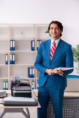 Young employee making copies at copying machine 