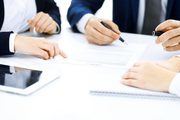 Group of business people and lawyers discussing contract papers sitting at the table, close-up. Successful teamwork, cooperation and agreement concepts