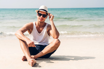 Smiling handsome man relax in sunglasses and straw hat on the tropical beach.Summer vacations