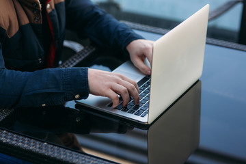 Close up of man using laptop on the table. Cappuchino on the glass table