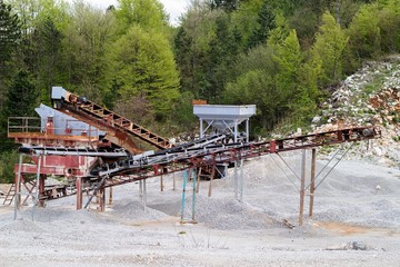 Rock stone crushing machine against a blue sky, close-up. Mining industry. Quarry and mining equipment