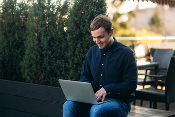 Man typing on his laptop. Backgroung of green tree