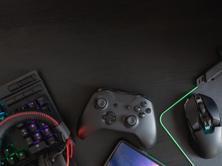 gamer workspace concept, top view a gaming gear, mouse, keyboard, joystick, headset, mobile joystick and mouse pad on black table background with RGB color. © ekkaphan