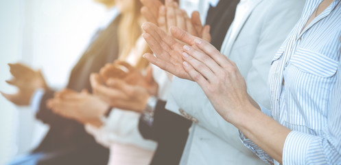 Business people clapping and applause at meeting or conference, close-up of hands. Group of unknown businessmen and women in modern white office. Success teamwork or corporate coaching concept - obrazy, fototapety, plakaty