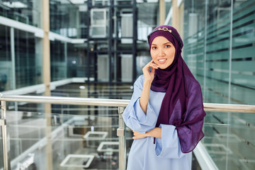 Portrait of a beautiful Arabian Woman in her 20th wearing Hijab and blue long dress posing for fashion magazine in modern interior.