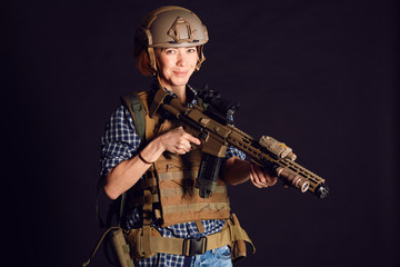 Fototapeta na wymiar Female civil in tactical uniform with rifle. Shot in studio on black background. Woman citizen forced to defend herself