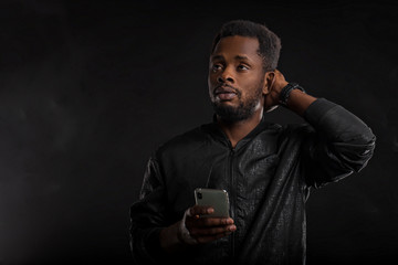 Black man holding mobile phone in dark