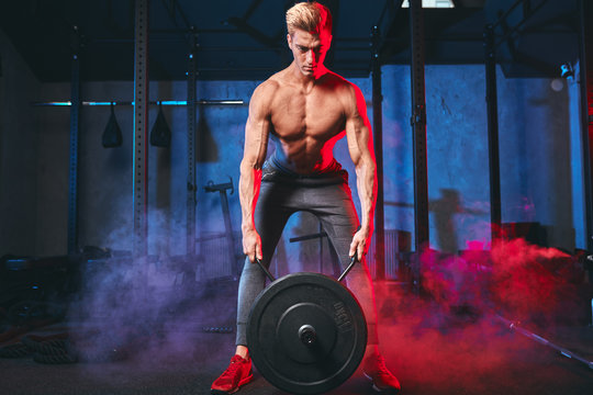 Power Athletic Male Bodybuilder Champion Doing Exercises With Heavy Weight Barbell Plate In Gym, Pumping Up Muscles To The Next Contest