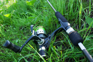 Fishing rod on the grass. The coil with a green cord on a spinning. Fishing.