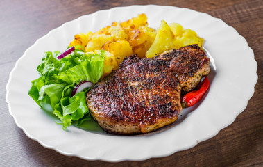 Pork Loin chops marinated meat Steak with vegetables slad and potato on wooden table background