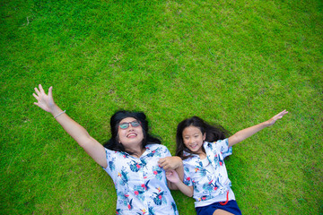 Mom and daughter happy lying on the grass ,top view