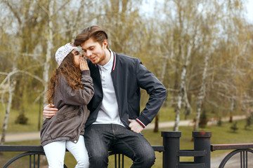 Little sister telling secrets to her brother at the park. Empty space