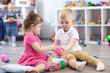Little toddlers boy and a girl play together in nursery room. Preschool children in day care centre