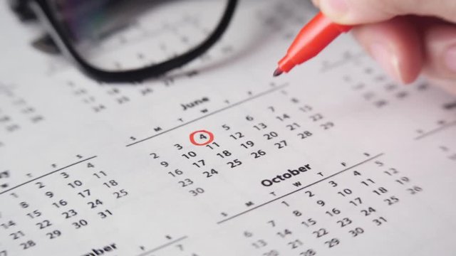 Signing a day on a calendar with red pen or marker. Crossing dates