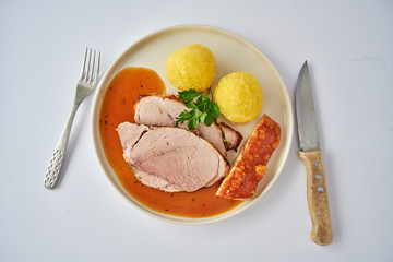 Deutscher Schweinebraten mit Kruste und Knödel auf weißem Hintergrund top view restaurant