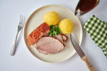 Deutscher Schweinebraten mit Kruste und Knödel auf weißem Hintergrund top view restaurant