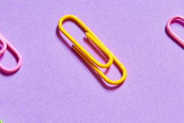 yellow paper clip between pink ones, close up photo. connection element