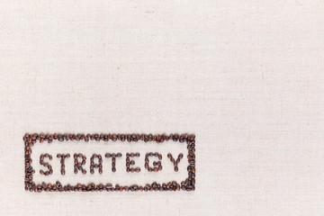The word Strategy inside a rectangle all made using coffee beans shot from above, aligned at the bottom left.