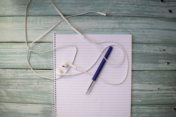 phone headphones, notebook and pen on the desktop