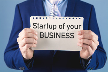 businessman holding a paper with the inscription startup of your business